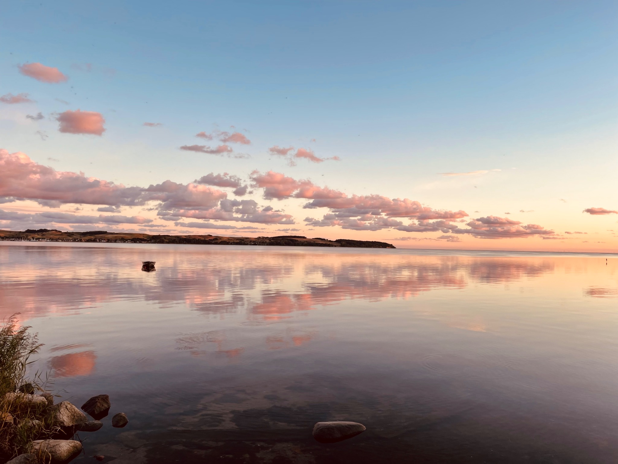 Rosa Abendwolken spiegeln sich auf dem weiten, ruhigen Bodden