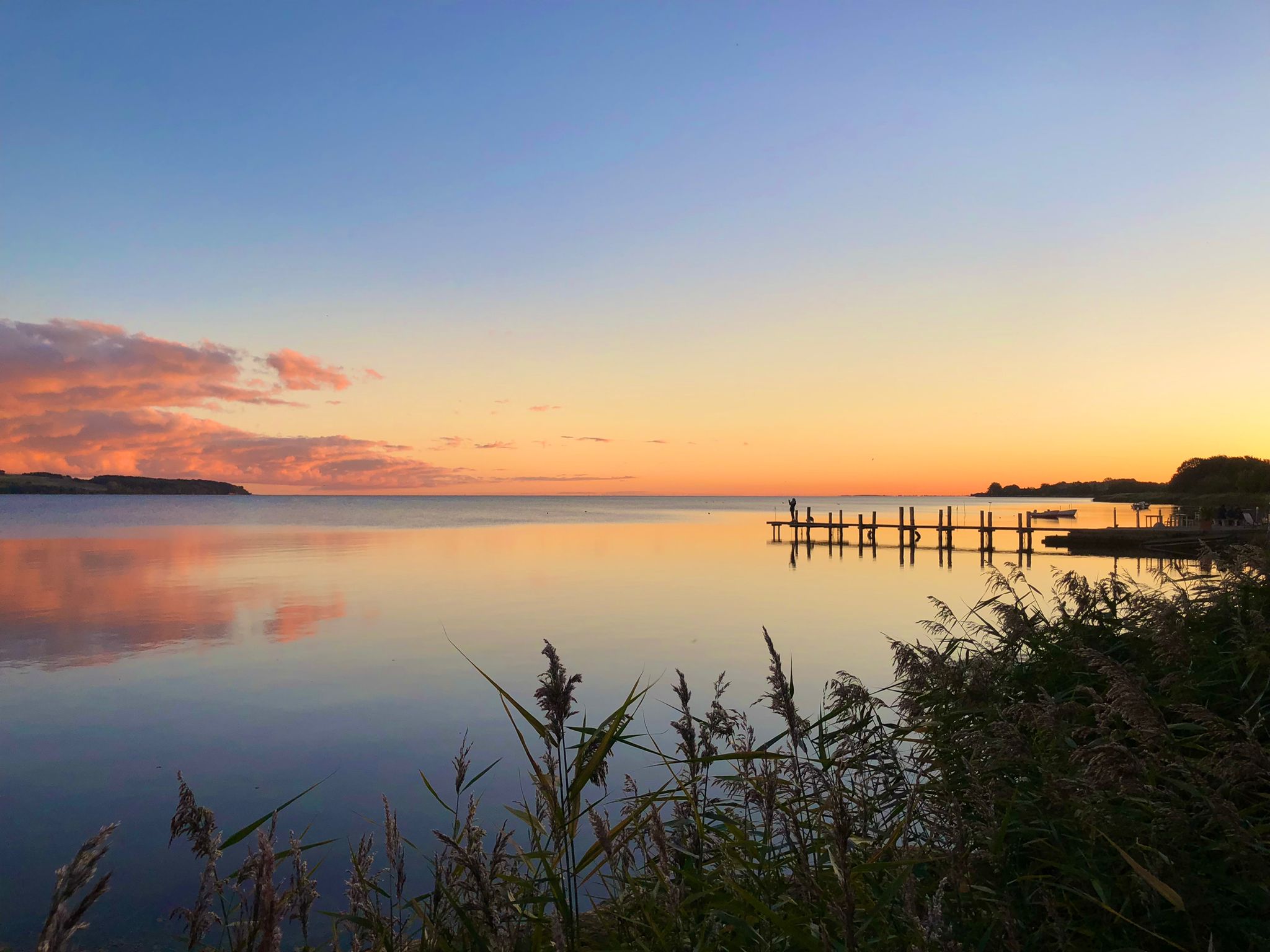 Abendlicht vor unserem Restaurant: stilles Wasser, weiter Horizont und ein kleiner Steg