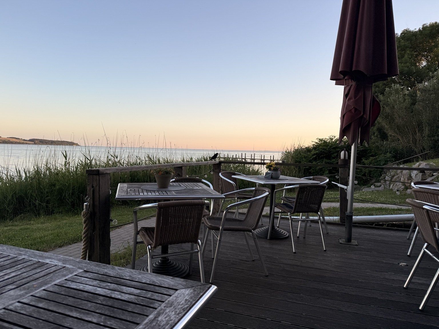 Vom Sitzplatz auf der Terrasse hinaus auf das ruhige Wasser im Abendlicht
