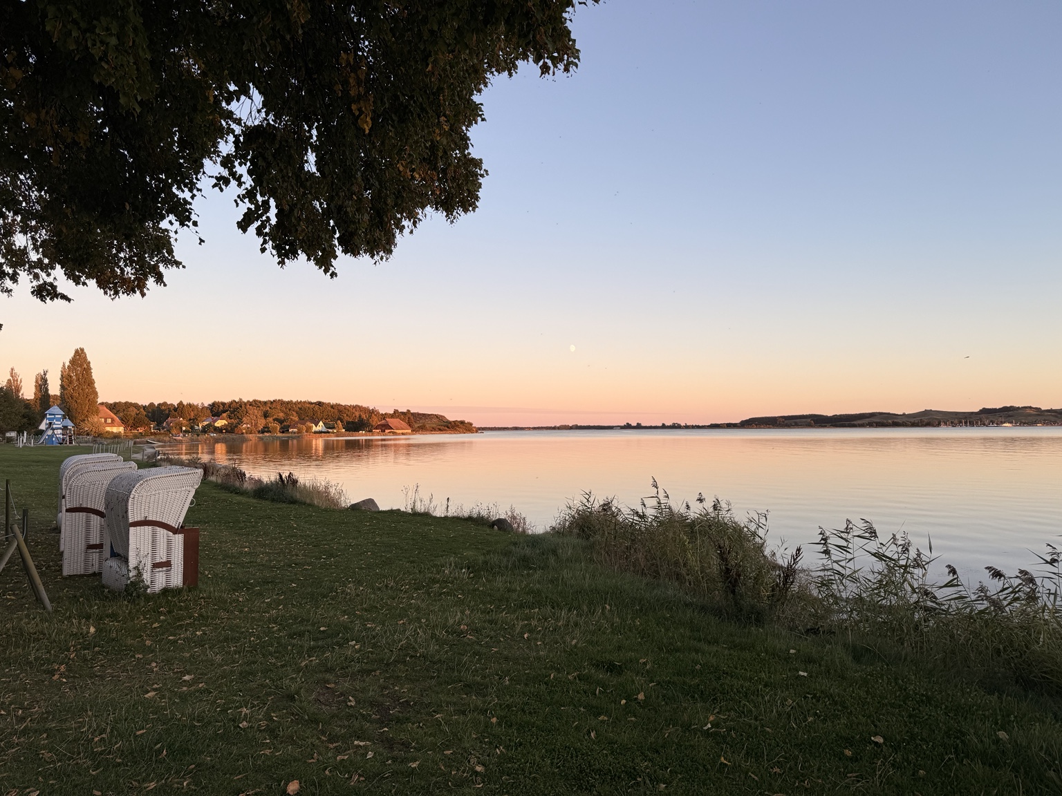 Strandkörbe am Ufer und der weite Bodden im warmen Abendlicht