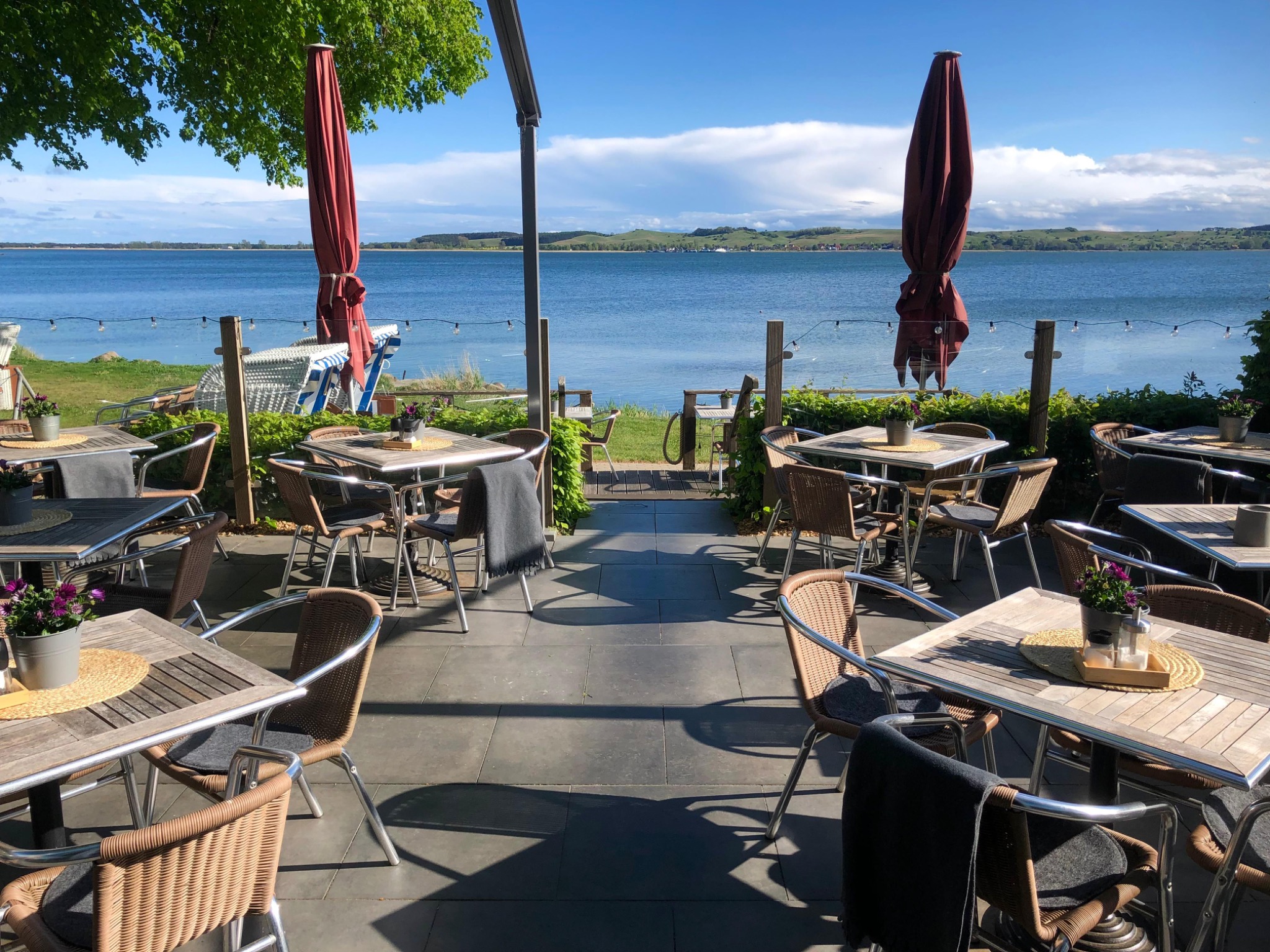 Sonnige Terrasse direkt am Bodden mit gedeckten Holztischen
